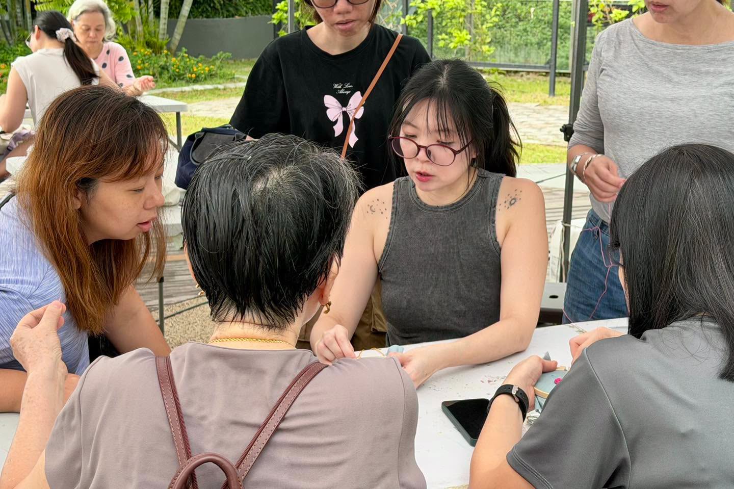 Participants socialising at an outdoor table during the embroidery workshop