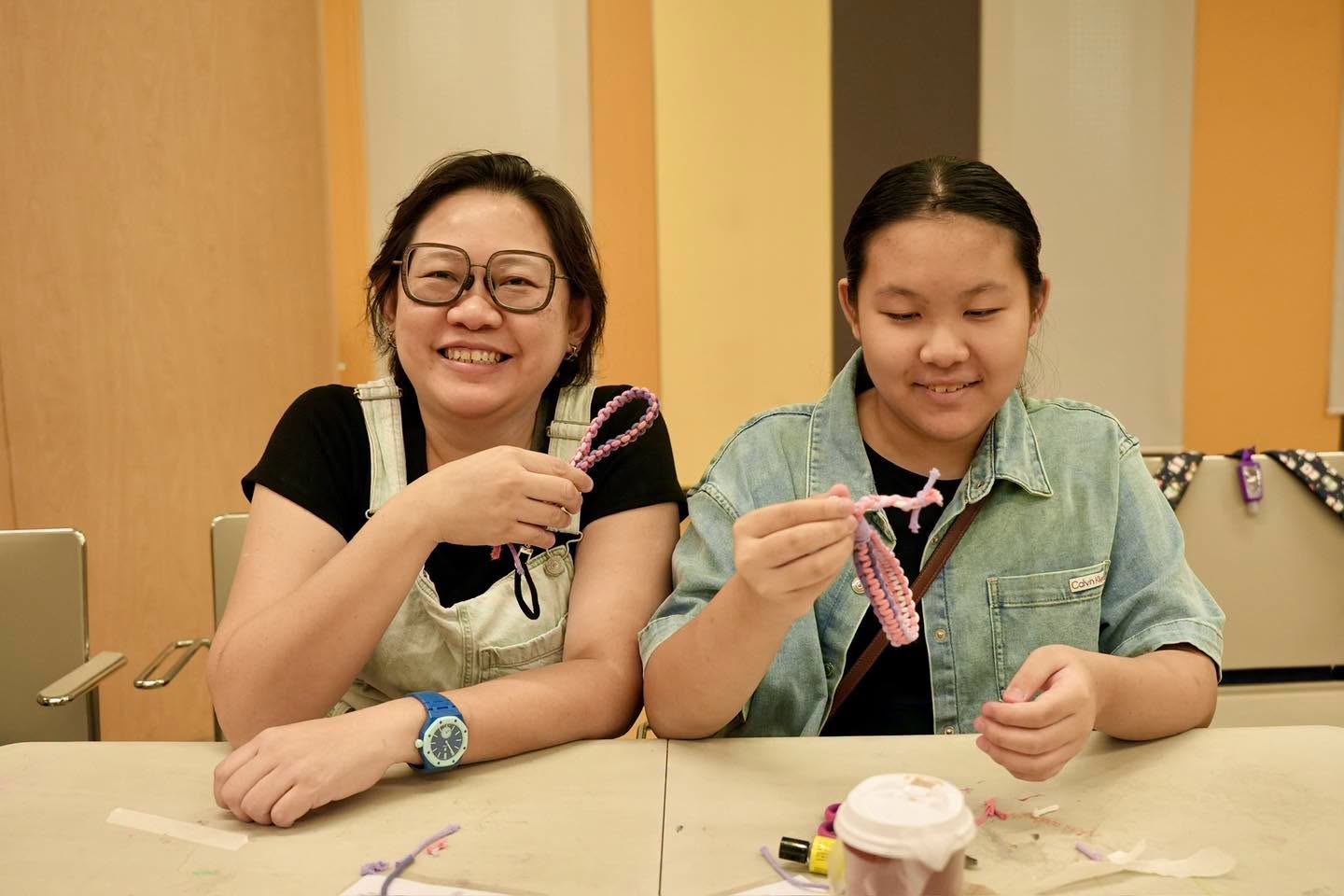 Two participants crafting yarn bracelets at the workshop