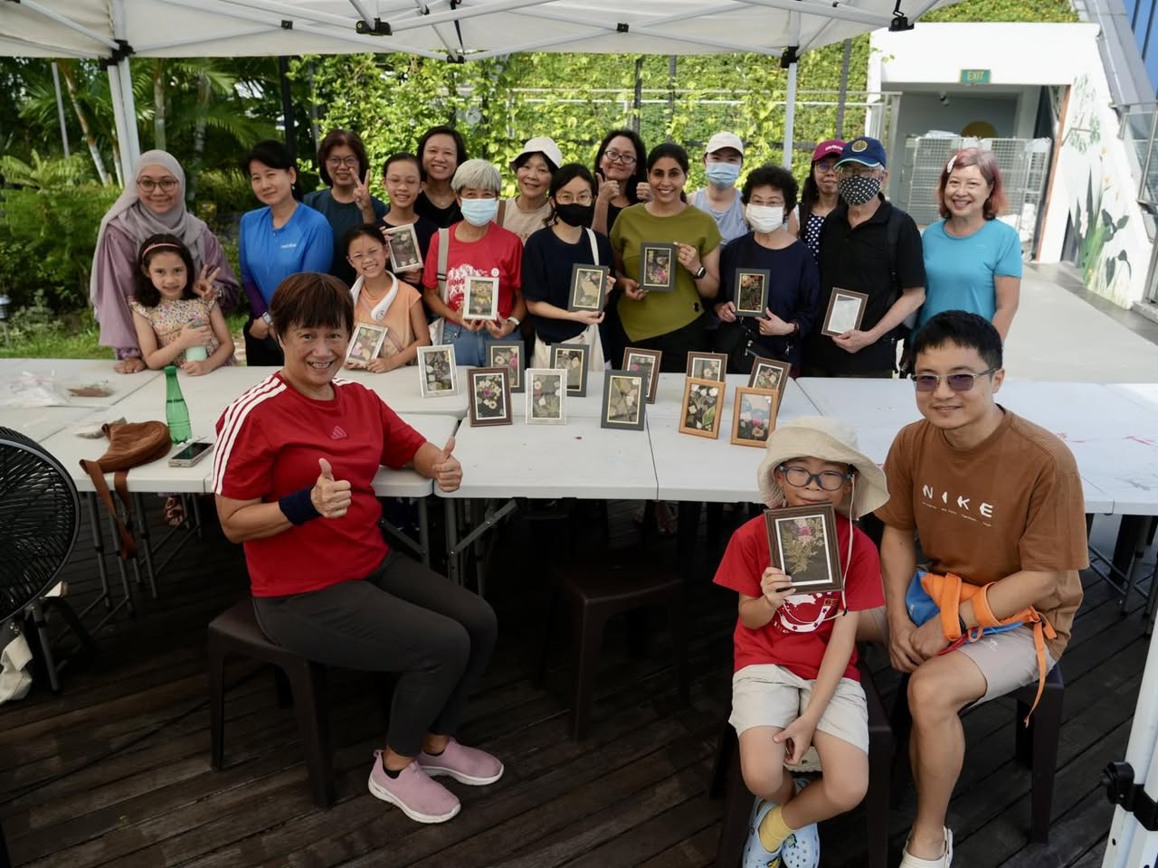 A group of participants proudly displaying their pressed flower creations.