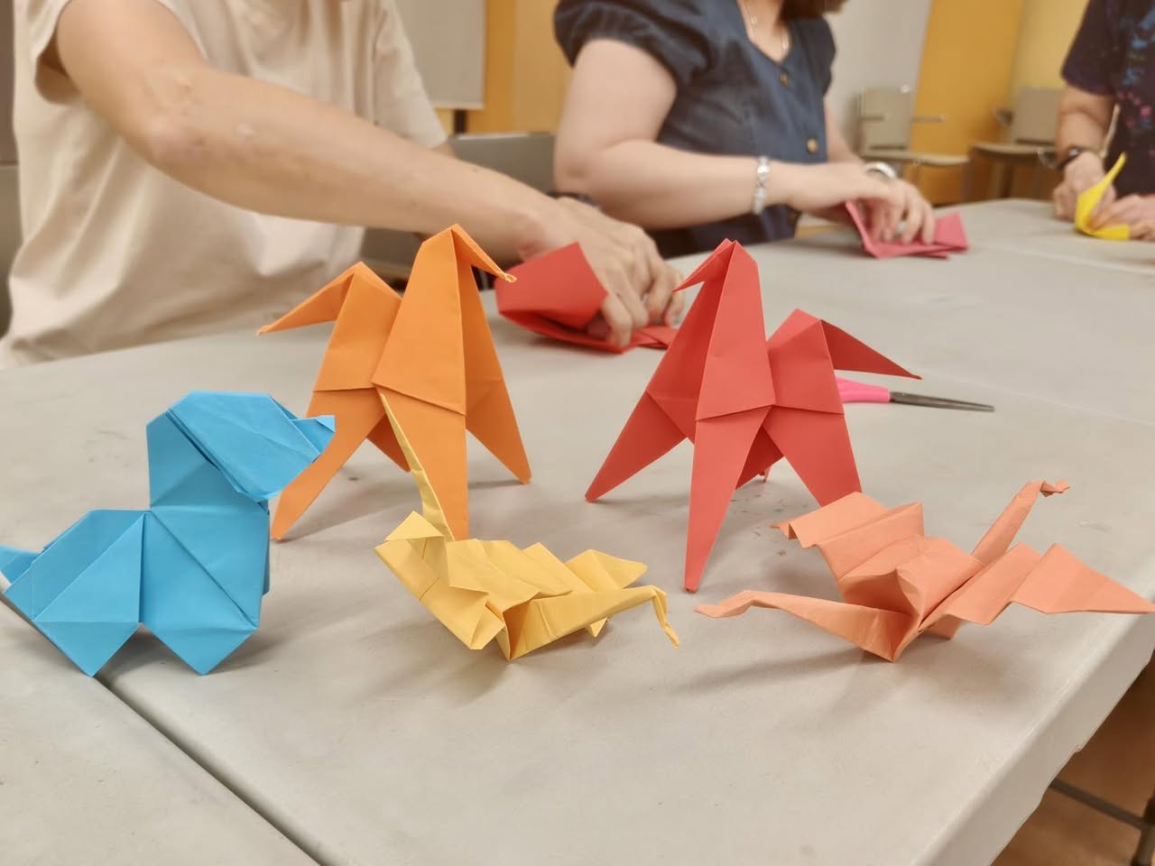A group of happy participants showcasing their finished origami artwork.