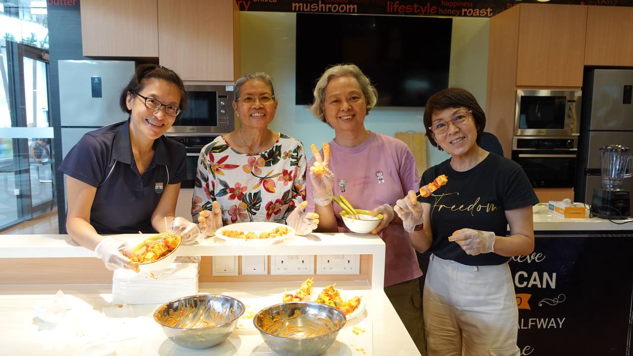 A group of smiling participants holding their prepared tikka skewers.
