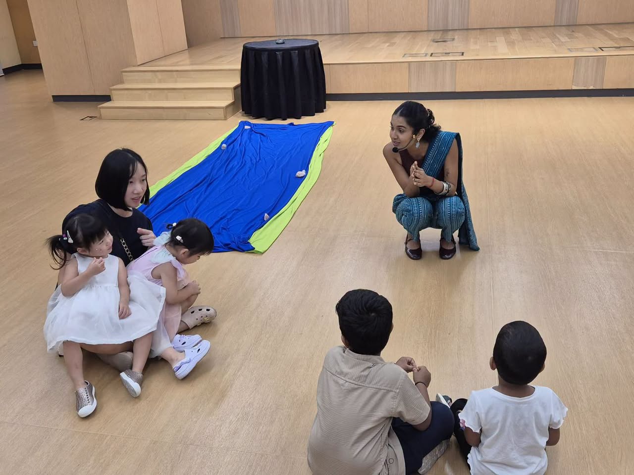Children gathered around parachute mat during ACT 3 Theatrics session