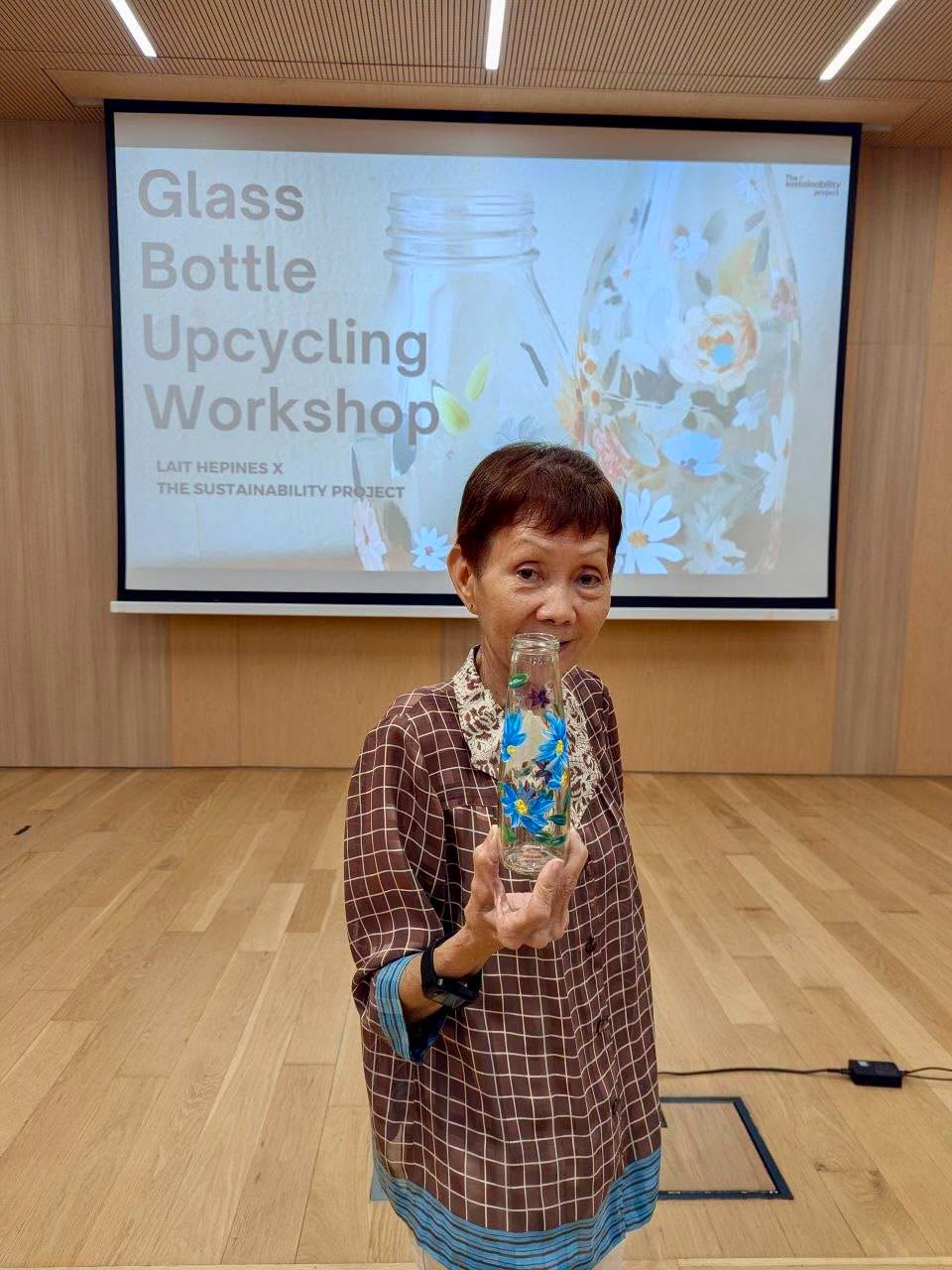 Participant decorating a glass bottle with floral designs at the workshop