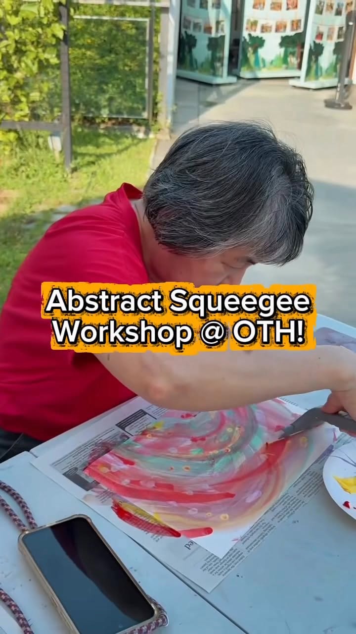 Participant creating abstract squeegee painting with vibrant red, pink, yellow and blue acrylic colours at OTH Wellness Garden workshop