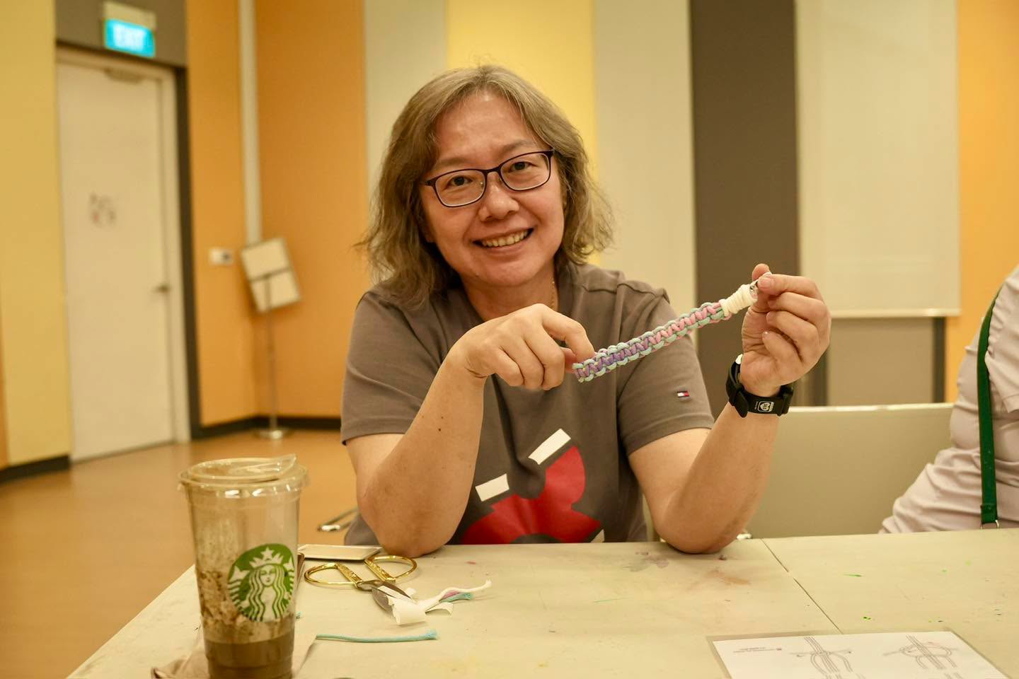 A participant holding a colourful woven bracelet during the workshop