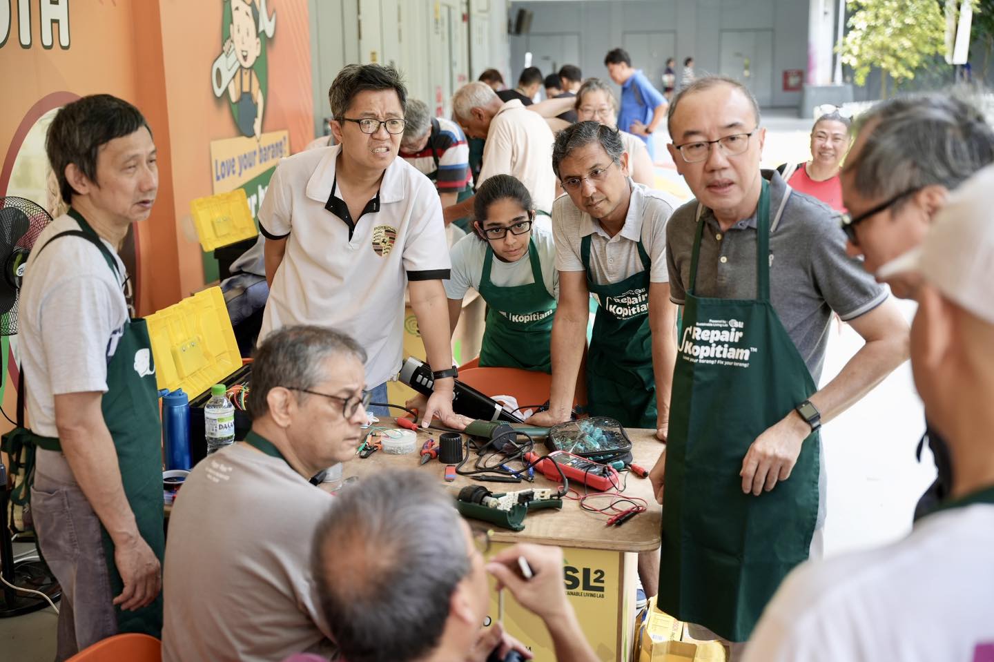 Volunteer coaches assisting residents with repairs at Repair Kopitiam.