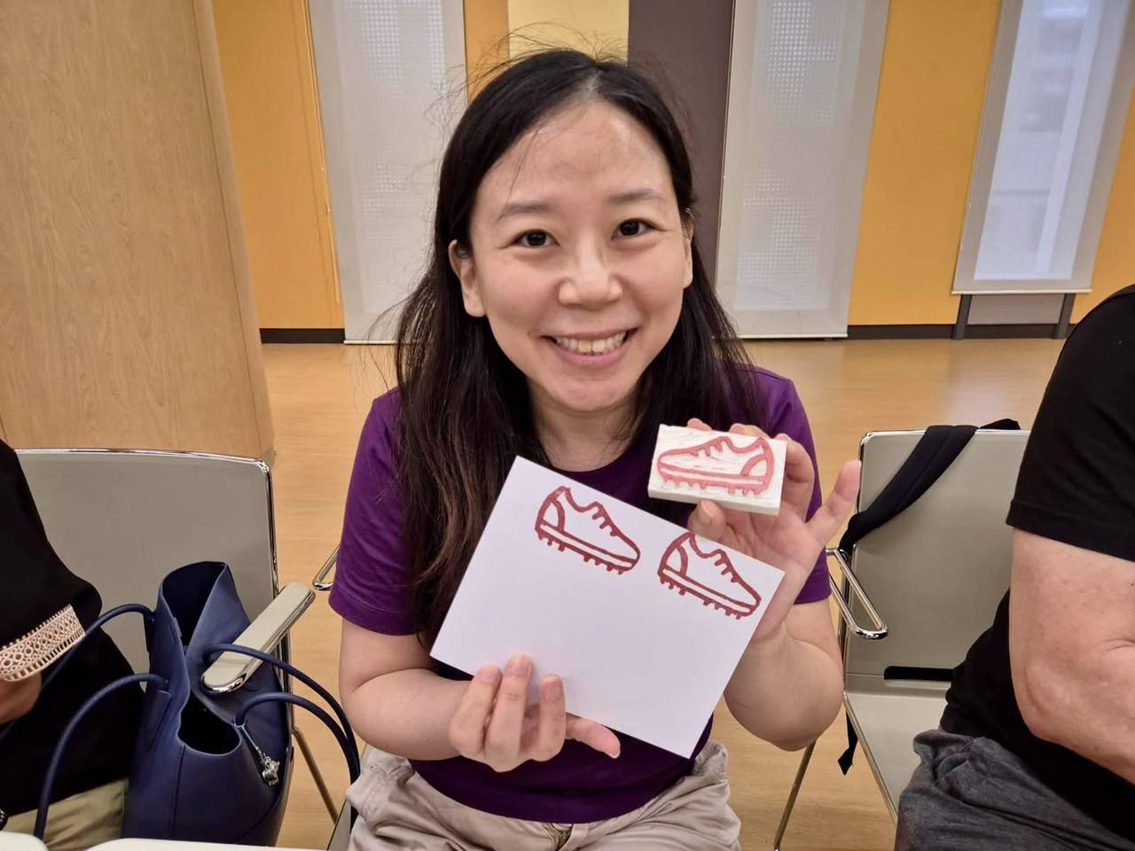 Workshop participant holding a card with red shoe line drawings and a shoe-shaped block