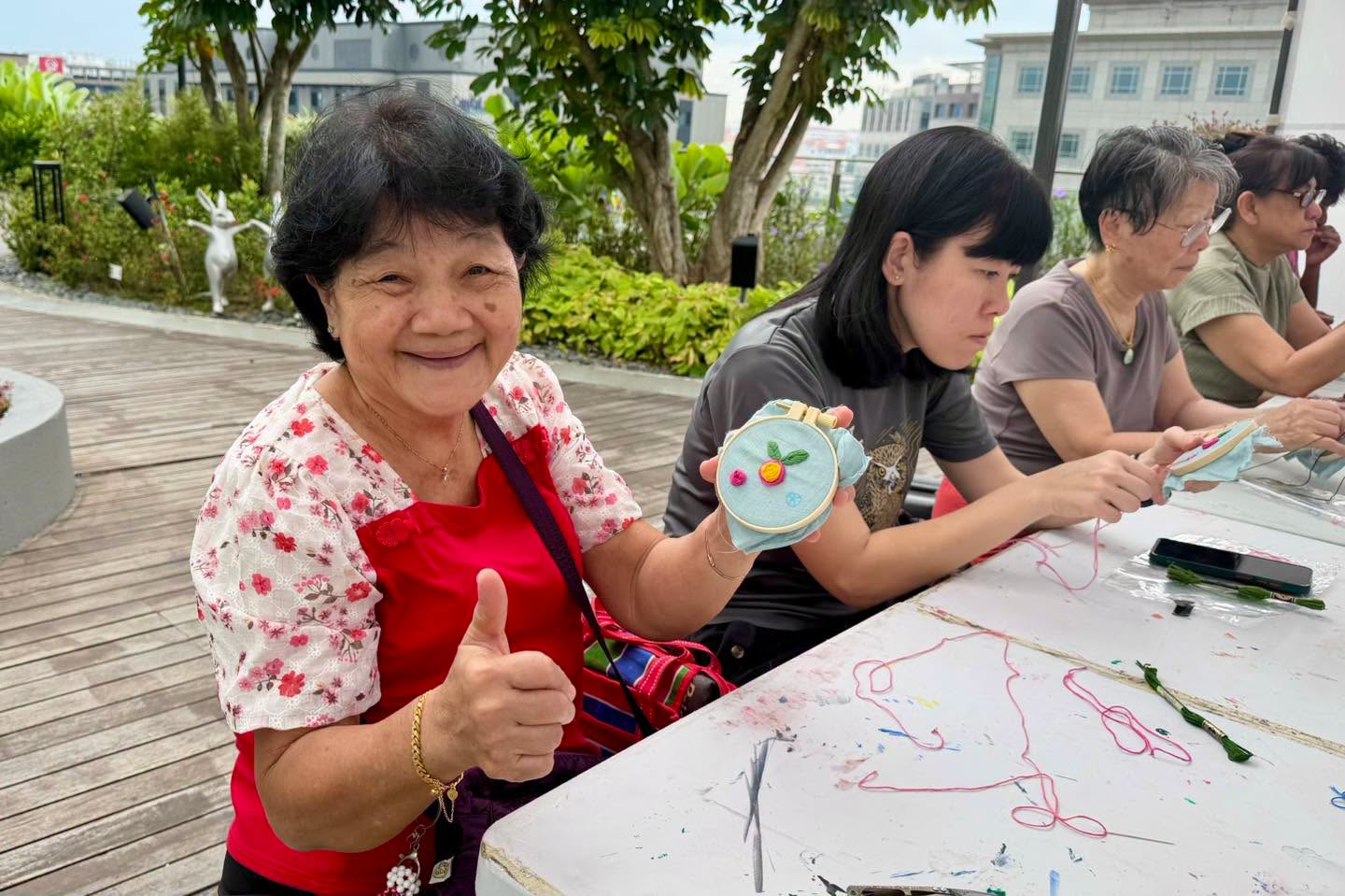 Participants embroidering at tables in the OTH Wellness Garden outdoor space