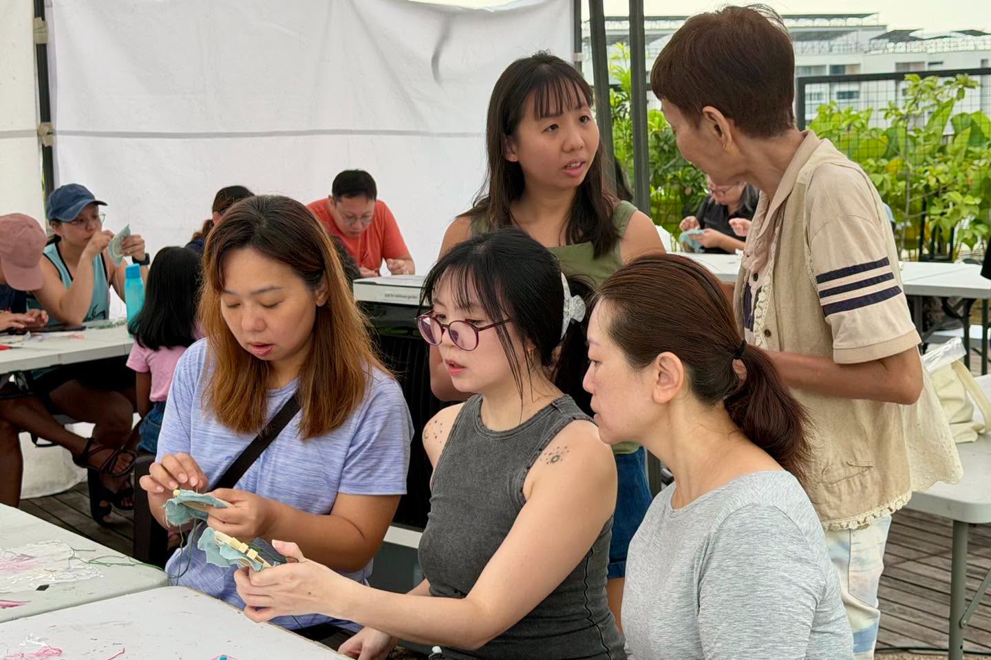 Group of participants crafting together under a white tent at the OTH Wellness Garden